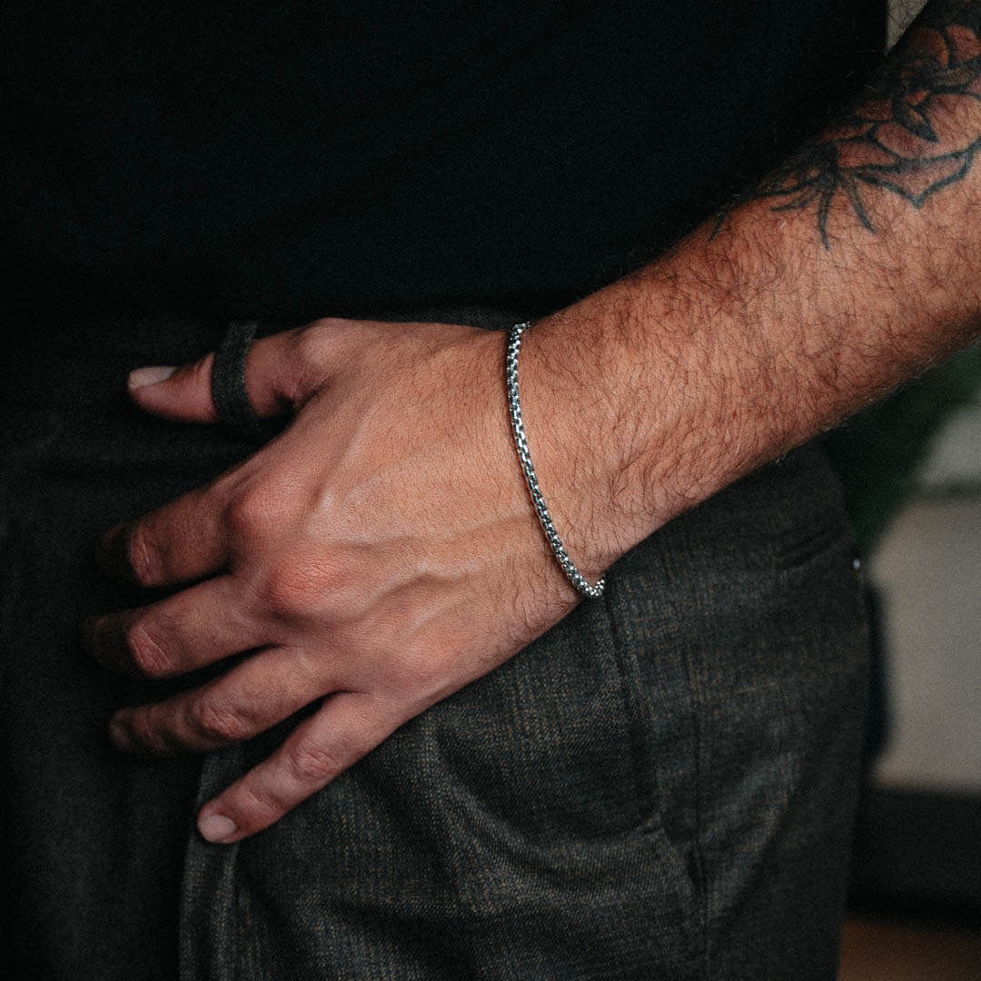 Man wearing thin silver round box bracelet around wrist