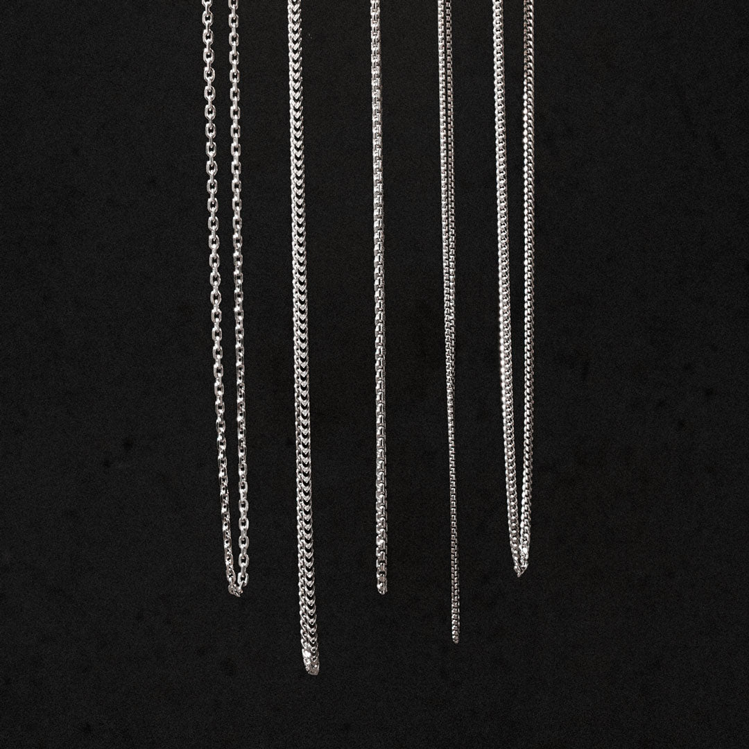 Sterling silver chain necklaces hanging on a black background