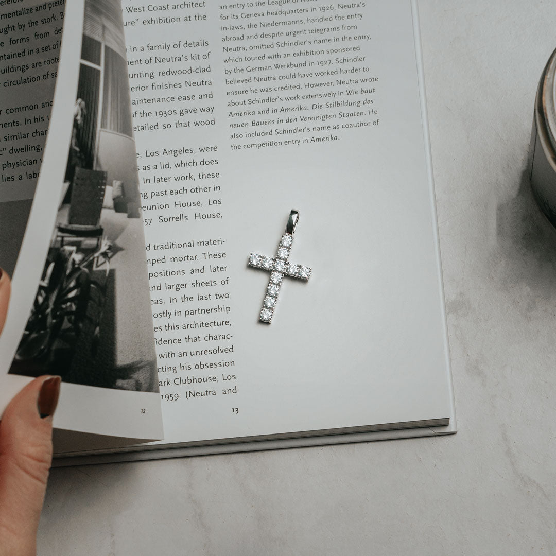 Diamond Cross pendant made of sterling silver laying on top of book