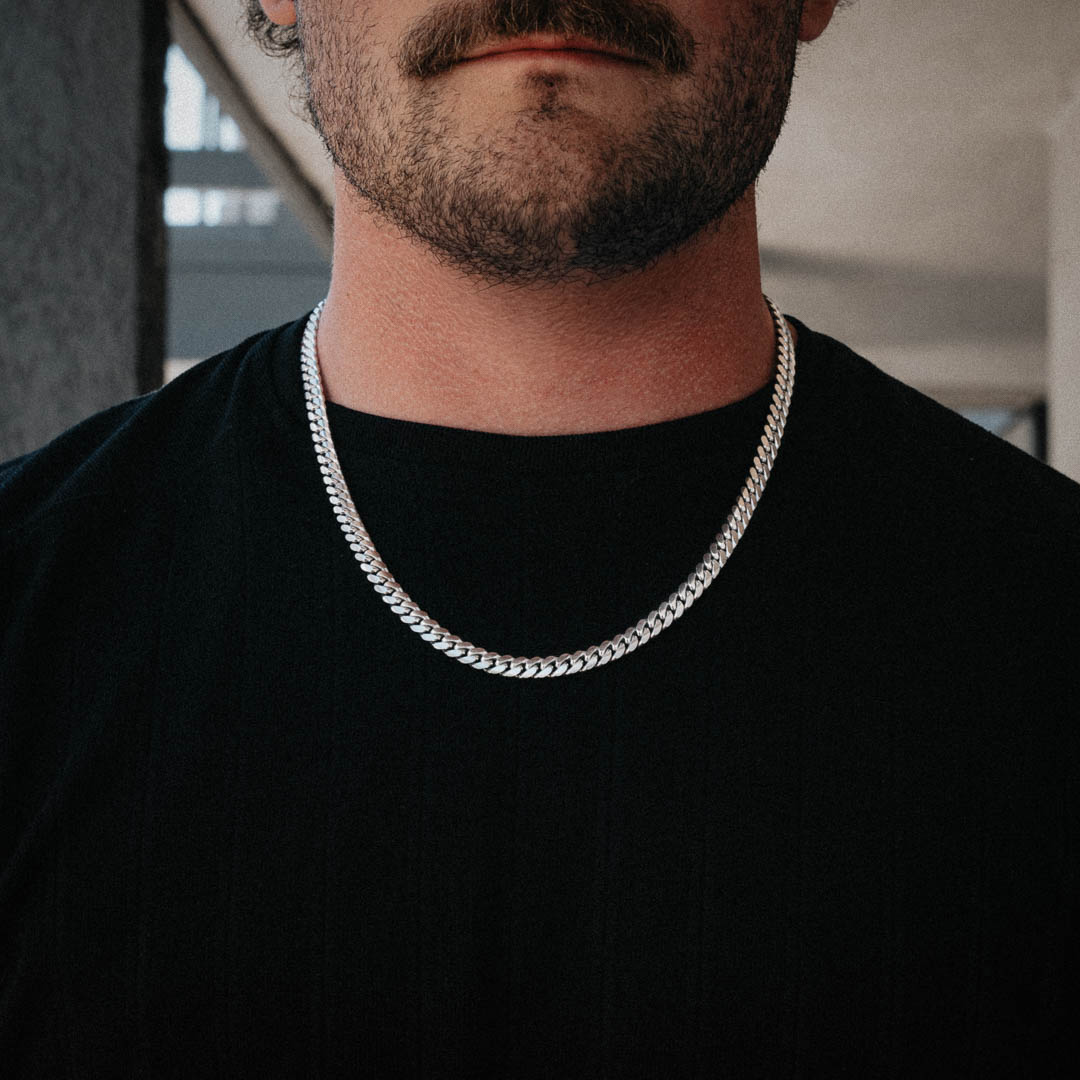 Close-up of a man wearing a thick sterling silver Cuban chain over a black t-shirt. Size: 22"