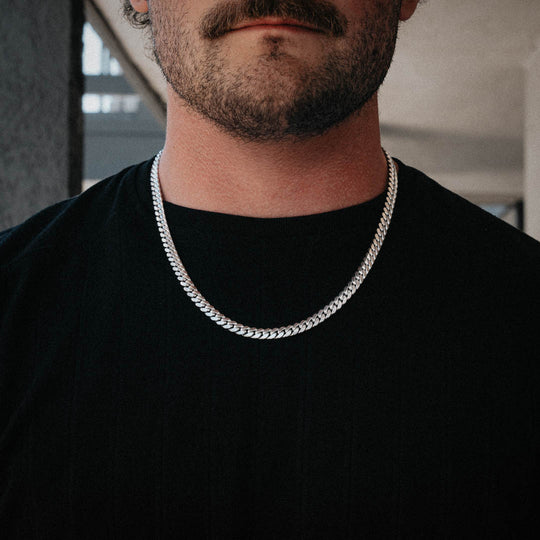 Close-up of a man wearing a thick sterling silver Cuban chain over a black t-shirt. Size: 22"