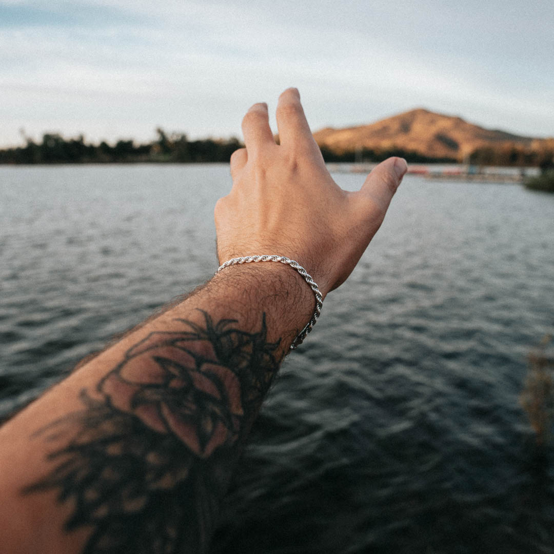 Silver rope bracelet on wrist over water